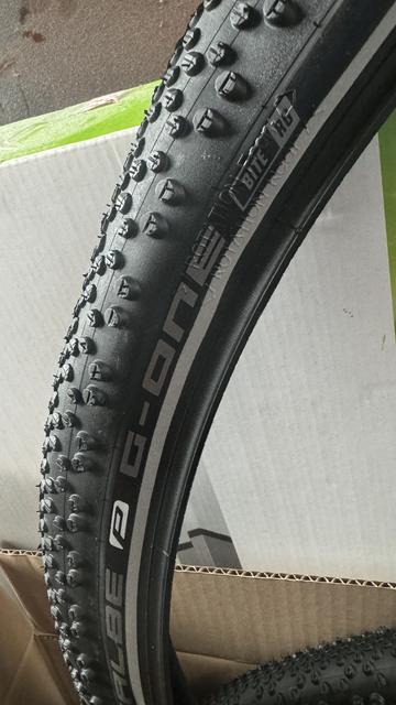 Nahaufnahme eines Schwalbe G-One Bite-Reifens, der seine Lauffläche und Teilverpackung zeigt.