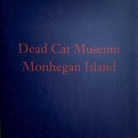 A softcover book with a dark blue background. Red letters of the title spell out two titles: 'Dead Cat Museum' and 'Monhegan Island'. Both are names of paintings by American artist Jamie Wyeth. The book is an exhibition catalog for a 1999 show of works by this artist at the gallery of James Graham & Sons in New York City.