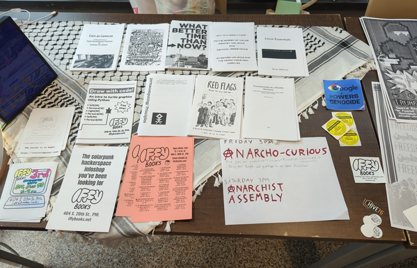 A table with zines, many of them from Iffy Books. Topics range from permacomputing to avoiding vanguard communist groups to dealing with surveillance from Tesla car cameras.