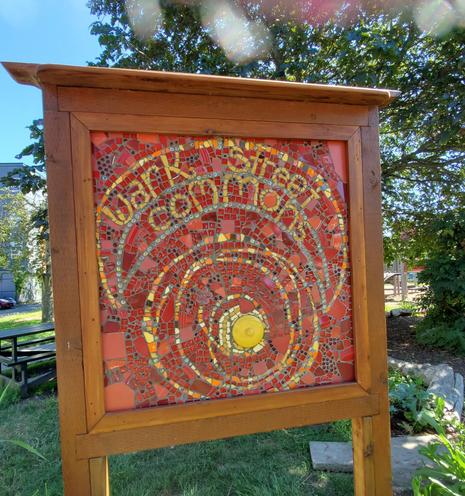 Large mosaic art sign, with words, Wark Street Commons, on it, mounted in wood frame & posts, at entrance to park.