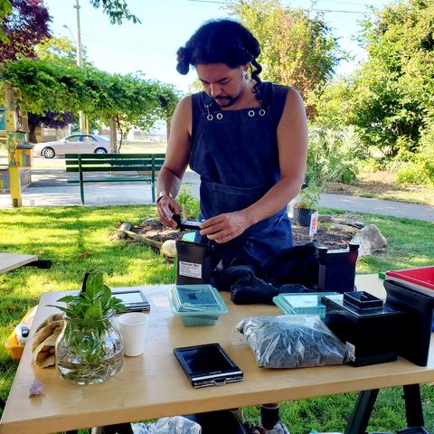 Joshua, guest artist & analogue photographer, loading film cases on table that's full of workshop supplies.