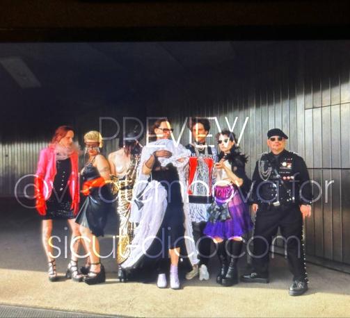 7 people including Sicut and Gene dressed in fashionable clothes standing in a line, looking hot and exhausted