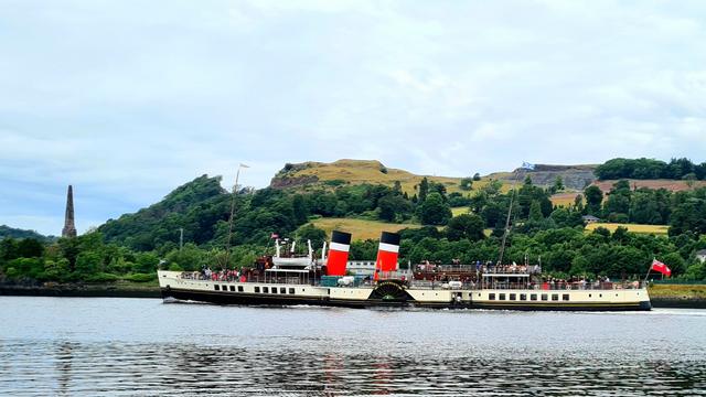 An old paddle steamer passing a monument on the far shore as travels down the Clyde.