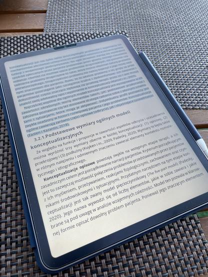 Zdjęcie iPada na stole ogrodowym z otwartą w nim książką „Konceptualizacja w terapii poznawczo-behawioralnej”