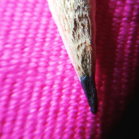 Macro de la punta de un lápiz sobre una tela rosa