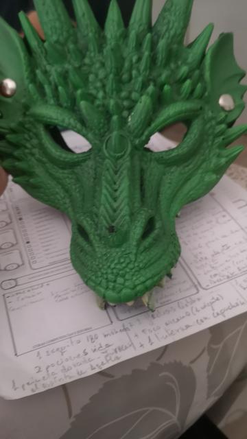 Foto de una máscara de dragón de fantasía de color verde sobre una ficha de personaje de Dragones y mazmorras.
