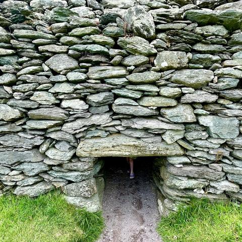 Stone structure with a small, narrow entrance partially obscured by a child standing inside.