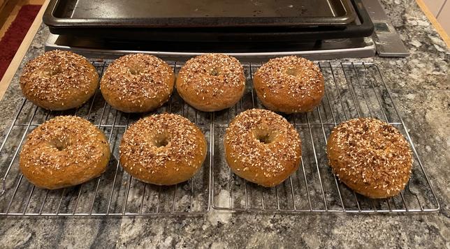 seven two-thirds-of-everything bagels and one half-of-everything bagel, which lacks rock salt, on a cooling rack atop a granite tile countertop