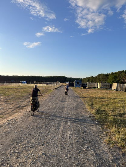 Zwei Radelnde befahren das im Aufbau befindliche Festivalgelände