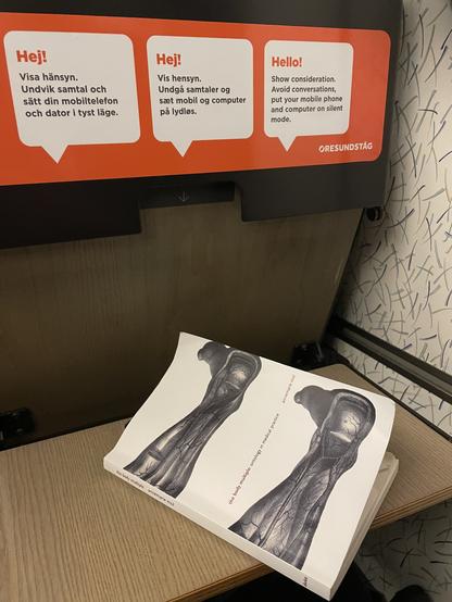 The book The body multiple lays on a table on a train