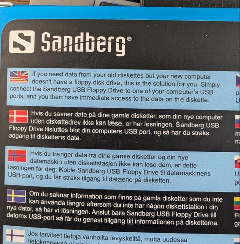 The back of a USB floppy drive box. It reads in multiple languages: "If you need data from your old diskettes but your new computer doesn't have a floppy disk drive, this is the solution for you. Simply connect the Sandberg USB Floppy Drive to one of your computer's USB ports, and you then have immediate access to the data on the diskette."
