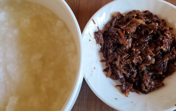 Plain congee in bowl on left. Minced, soy braised beef, in bowl on right.