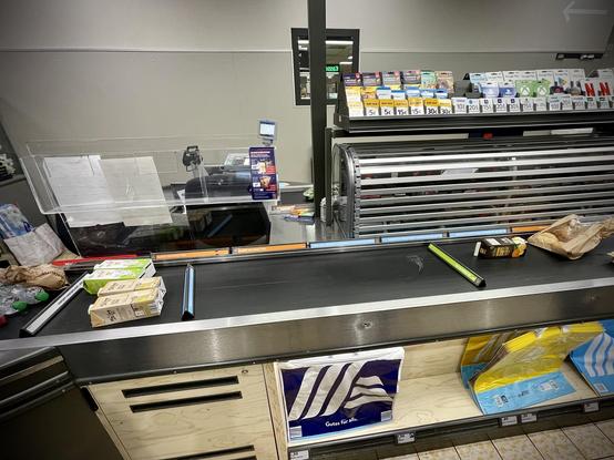 zu sehen ist das kassenförderband in einem discounter. links liegen vier einliter-tetrapacks mit milch und hafermilch. dann liegt ein kundentrenndingsbums auf dem band. ganz rechts liegt ebenfalls ware von jemand anderem, nach links ebenfalls abgetrennt durch das warentrennobjekt. zwischen diesen beiden trenndingern, also mittig in zentraler position im bild, ist einfach nichts.