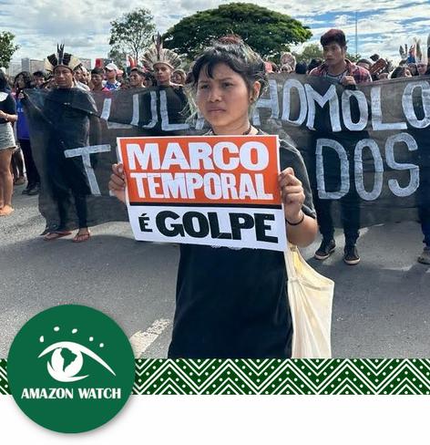 Woman holding up a sign saying Marco Temporal é golpe  

By Amazon Watch
