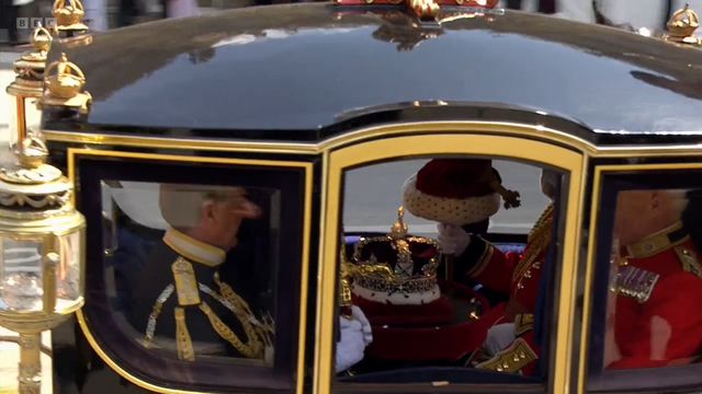 Lähikuva vaunujen sisään, jossa yhdellä ihmisellä on sylissään kuninkaan kruunu. 

Vaunuihin meni kolme ihmistä, jotka sitten ottivat nämä kruunut, miekat yms. mukaansa Westministeristä.