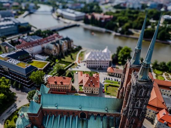 Aerial view of a city, featuring a prominent cathedral with twin spires in the foreground, surrounded by historic buildings, a river, and lush greenery in the background.

Widok z lotu ptaka na miasto, z wybitną katedrą z bliźniaczymi iglicami na pierwszym planie, otoczoną zabytkowymi budynkami, rzeką i bujną zielenią w tle.