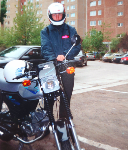 on the left side is a motorcycle right beside a person with a helmet is putting on the gloves.