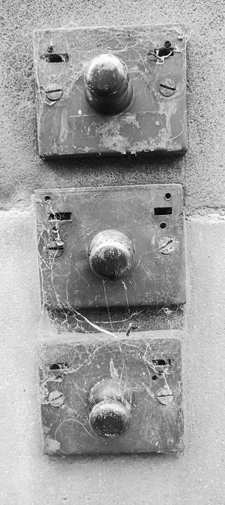 Old bell-pulls on an Edinburgh tenement, a mechanical system to ring a bell in an apartment in the days before electric intercoms and door buzzers, three one above the other, all draped in cobwebs