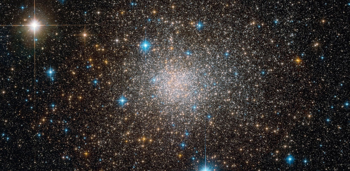 A giant, bedazzling jewel-like structure. The globular cluster is a collection of stars that are orbiting a common centre of gravity. This gives the cluster a spherical appearance. The many stars are densly packed in the core region and drop in density radially. The collection of stars is mostly white and yellow, but a few bright blue and red stars are also peppered around the cluster.