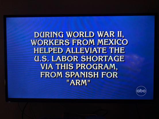 A photo of a television screen showing a Jeopardy clue:

DURING WORLD WAR II,
WORKERS FROM MEXICO
HELPED ALLEVIATE THE
U.S. LABOR SHORTAGE
VIA THIS PROGRAM,
FROM SPANISH FOR
"ARM"