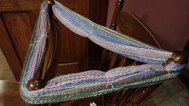 200 grams of multicolor two ply yarn, wrapped around three of the four top spokes of a pair of dining chairs. It's tied off in several places with crochet thread