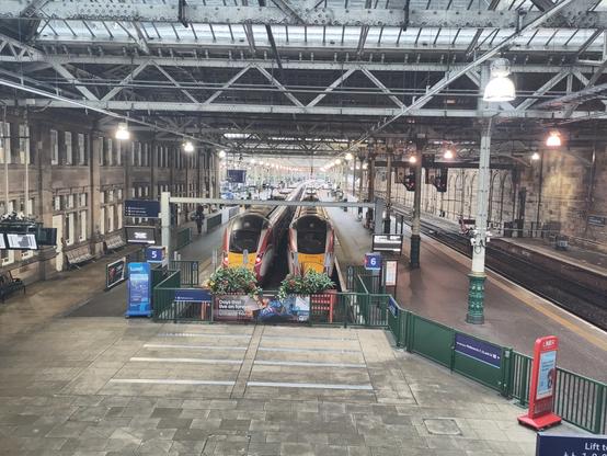 Two red and yellow trains side by side on the tracks.