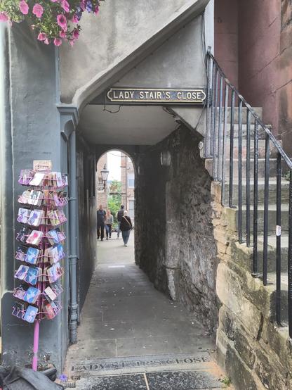 Lady Stair's Close (sign on the floor and above the "tunnel"), one of the many small passages through/under the building. A postcard stand on the left and a small stair  on the right.