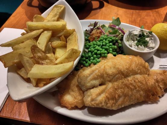 A fish and ships plate with a side of peas.