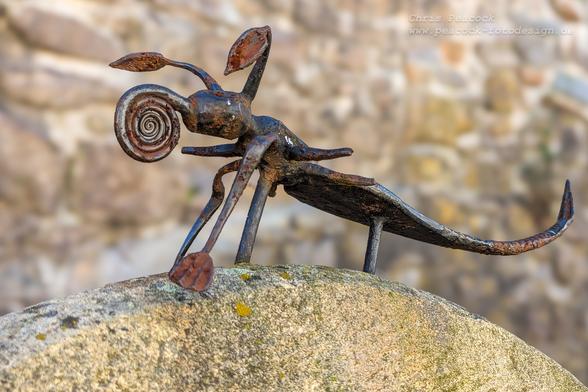 DE: Das Bild zeigt ein phantasievoll gestaltetes Kunstwerk aus Metall in Gestalt einer Mischung aus Insekt und Skorpion.

EN: The picture shows an imaginatively designed work of art made of metal in the shape of a mixture of insect and scorpion.

Lizenz / Licence: https://creativecommons.org/licenses/by-nc/4.0/deed.en