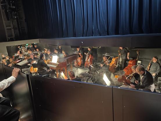 Orchestra warming up…stage lights and people in fancy dress; in the back the black theater curtain