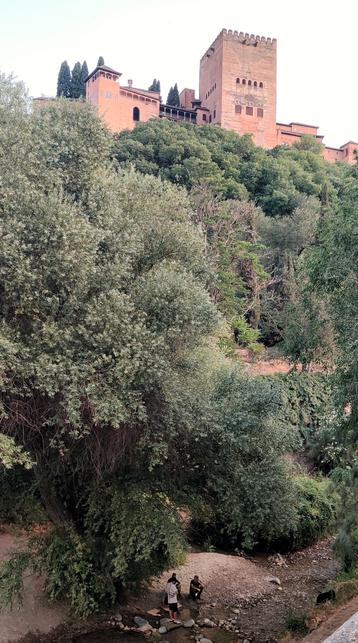 Un grupo de personas a orillas del río Darro, a los pies de la Alhambra.