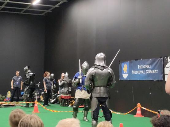 Kaksi metallipanssariin pukeutunutta tyyppiä yleisön keskellä.