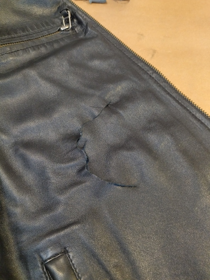 The tear in the front of the right side of the black leather jacket