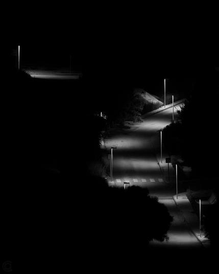 Black and white photo of tiny barely lit streets in Spain during the night