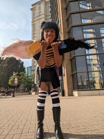 Me in Yohane (in this unstable world version, with black and white wings and a military esque uniform) cosplay bending forward with arms forward.