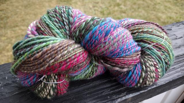 Large skein of multicolor two ply yarn. There's greens and blues and pinks, among other little bits of color, all barber pole around each other