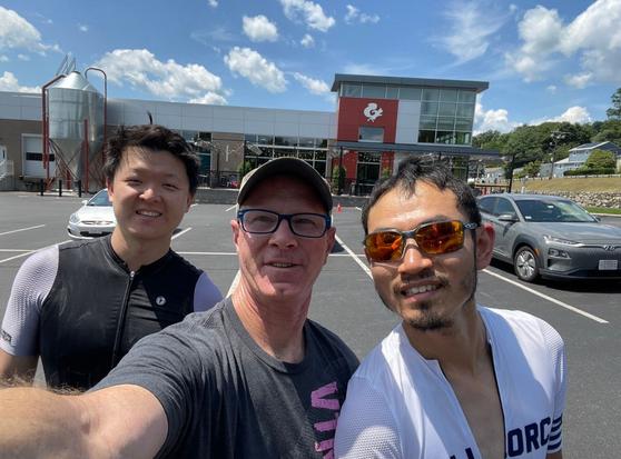 Three cyclists taking a selfie in front of The Mighty Squirrel brewery in Waltham MA.