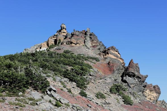A mountain view that reveals a unique assortment of geological volcano history. Various colors of rocks and shapes appearing squished together and carved away from past glacial periods & erosion.