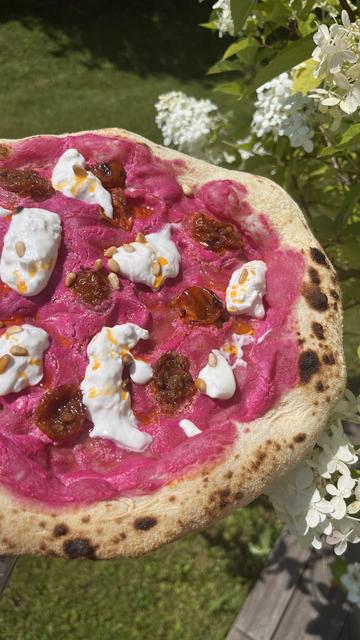 Pizza Neapolitan style with pink sauce half dried tomatoes burrata pine nuts and some sprinkles of orange spice oil