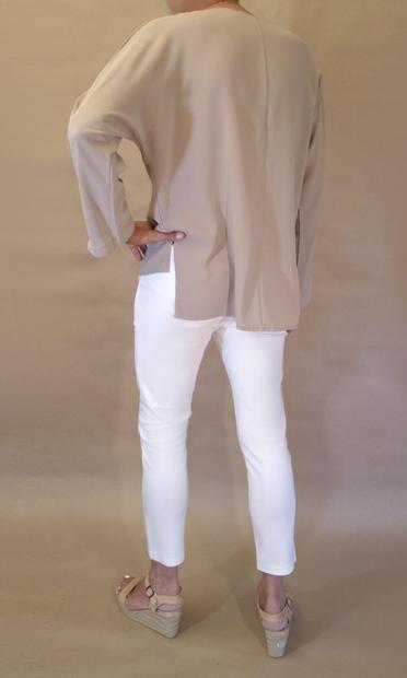 I’m wearing a loose closed khaki blouse with v-neck, white pencil pants with high ankles and a pair of light peach velvet ballerinas. Seen from the rear as I stand with left hand on my hip.