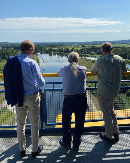Leiter der GDWS, Eric Oehlmann, Ralf-Rüdiger Dimmek, Leiter des WSA Oder-Havel und ein weiterer Begleiter der Gruppe schauen vom Besucherumlauf des neuen Schiffshebewerks auf das Panorama des Niederoderbruchs.