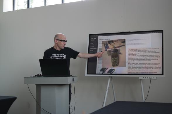 A speaker points at a presentation slide.