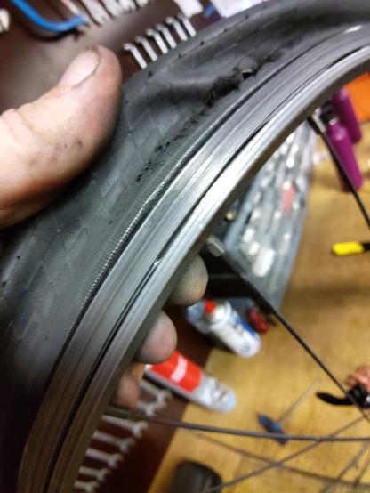 Détail d'une roue de vélo avec le pneu au flanc déchiré et la jante découpée sur le point de de s'éventrer