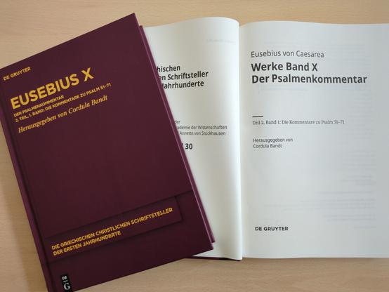 Phots des Einabndes und des aufgeschlagenen Titelblatts des Bandes, der auf einem Tisch liegt.