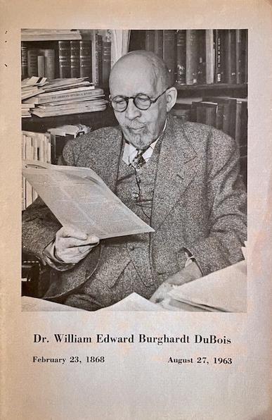 A paper pamphlet containing the funeral oration for African American activist and sociologist W. E. B. Dubois, which took place at the Aggrey Memorial Church at Achimota College in Accra, Ghana. Cover image shows a black & white photo of Dr. Dubois sitting at his desk, reading. A bookshelf is behind him and his desk is piled with papers.