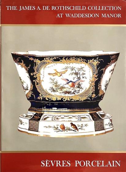 A large book about antique porcelain entitled 'The James A. De Rothschild Collection at Waddesdon Manor: Sevres Porcelain'. A large blue, white and gold Sevres charger with images of birds and fruit dominates the front cover.