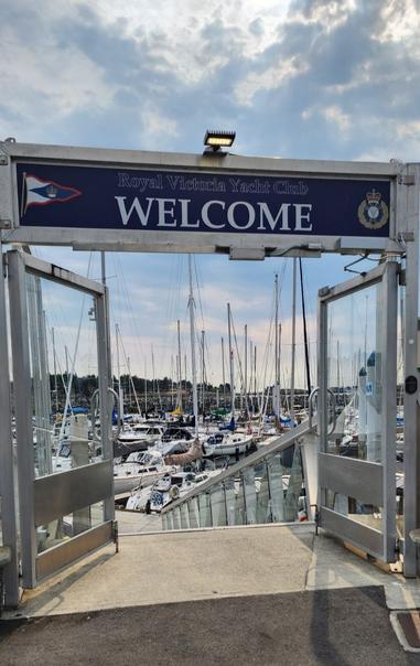 Welcome entrance to docks at Royal Victoria Yacht Club. Lots of yachts & boats are docked.