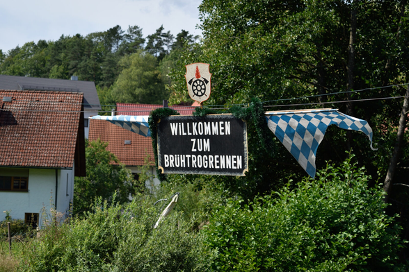 Schwarzes Schild mit der Aufschrift "Willkommen zum Brühtrogrennen"