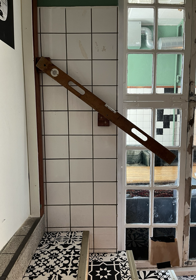 A photo of cafe interior, with a spirit level fixed on a wall above a staircase at 45-degree angle, to be used as a handrail.