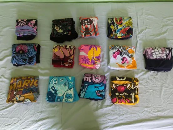 13 graphic t-shirts on a bed
